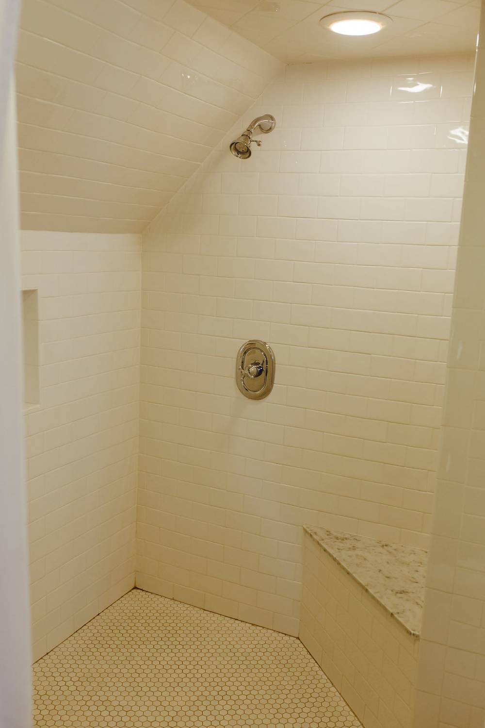 A very large walk in dual shower with a marble bench