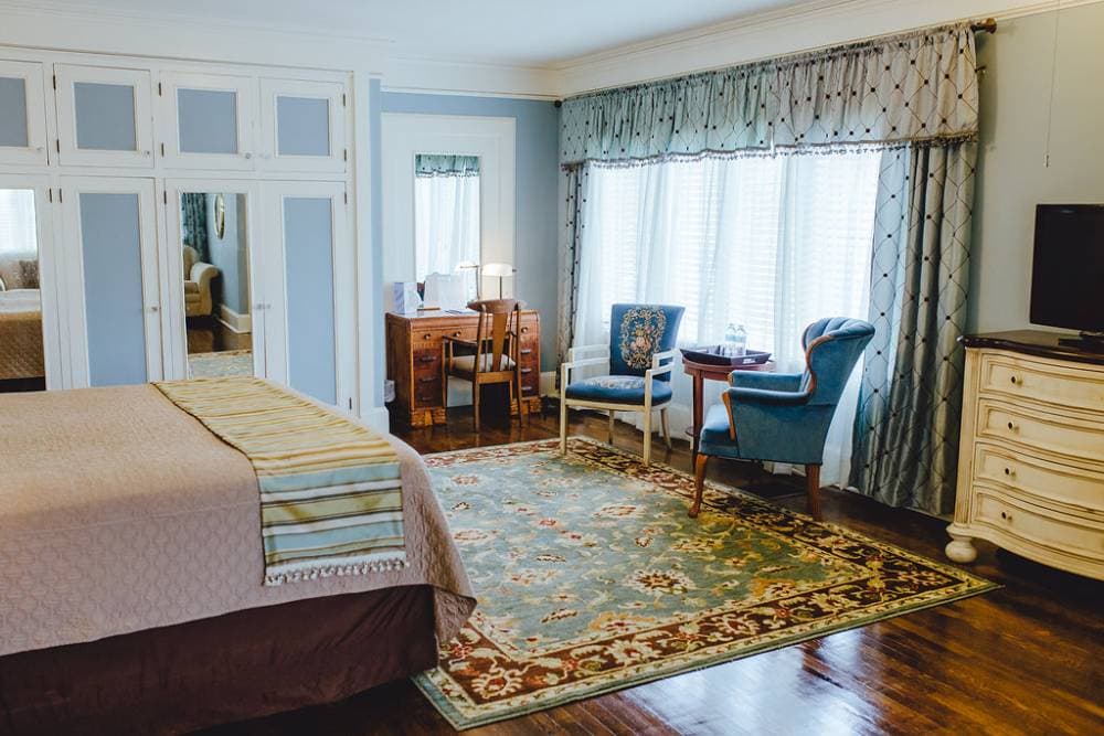 A small desk is located opposite the nook next to the large window and sitting area