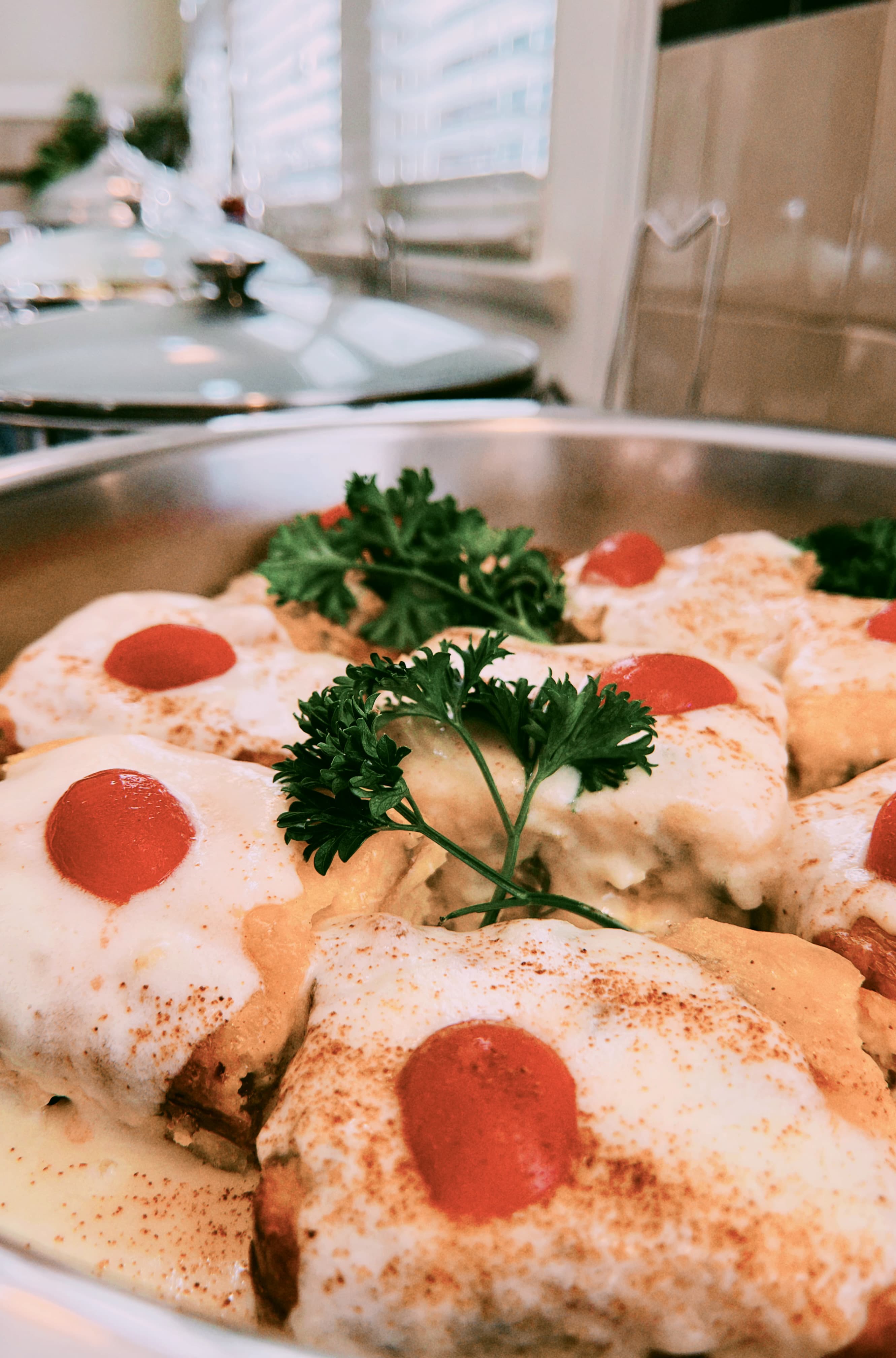 A close-up of a creamy dish topped with cheese, spices, and cherry tomatoes, garnished with parsley.