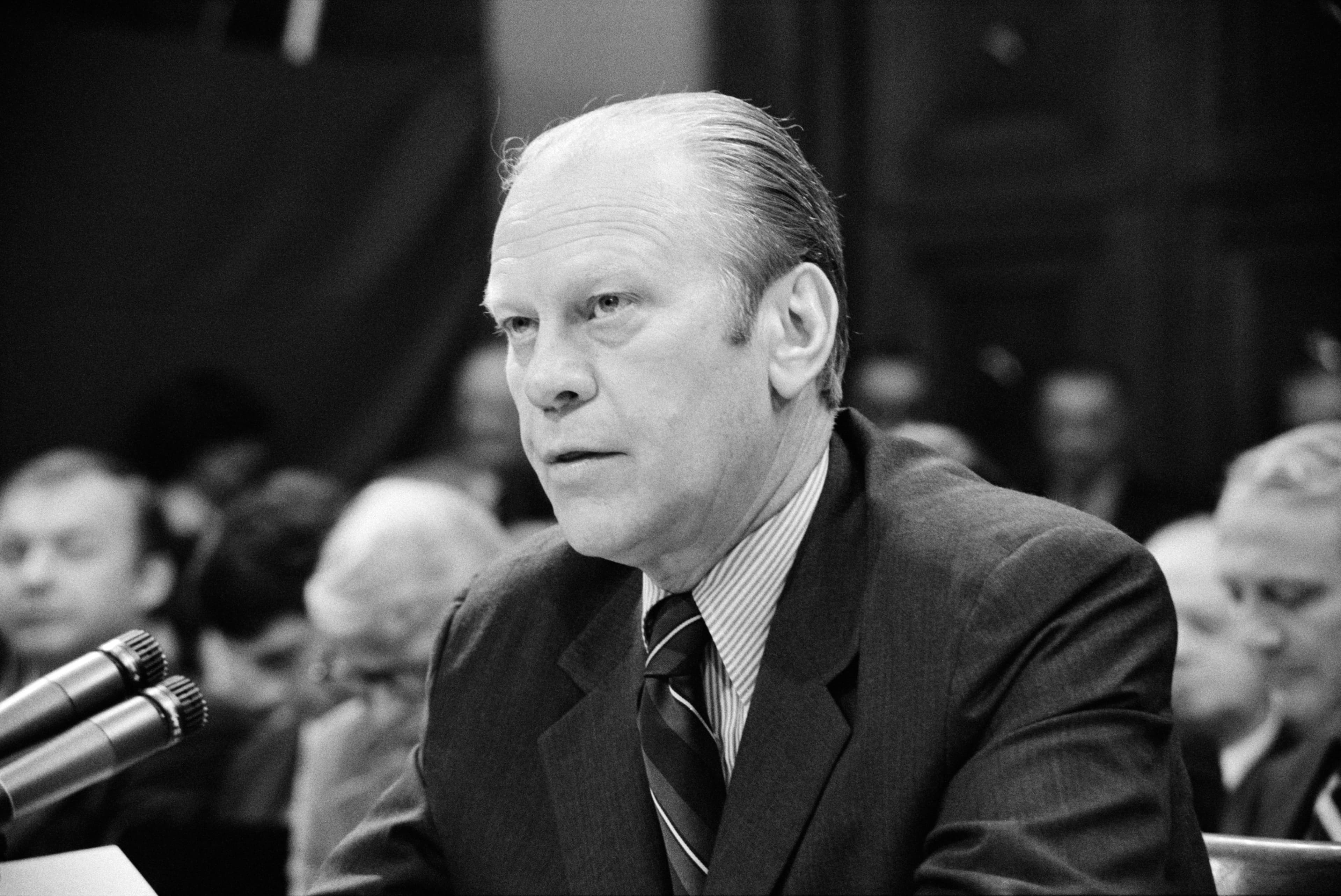 A man in a suit speaks at a microphone during a congressional hearing.