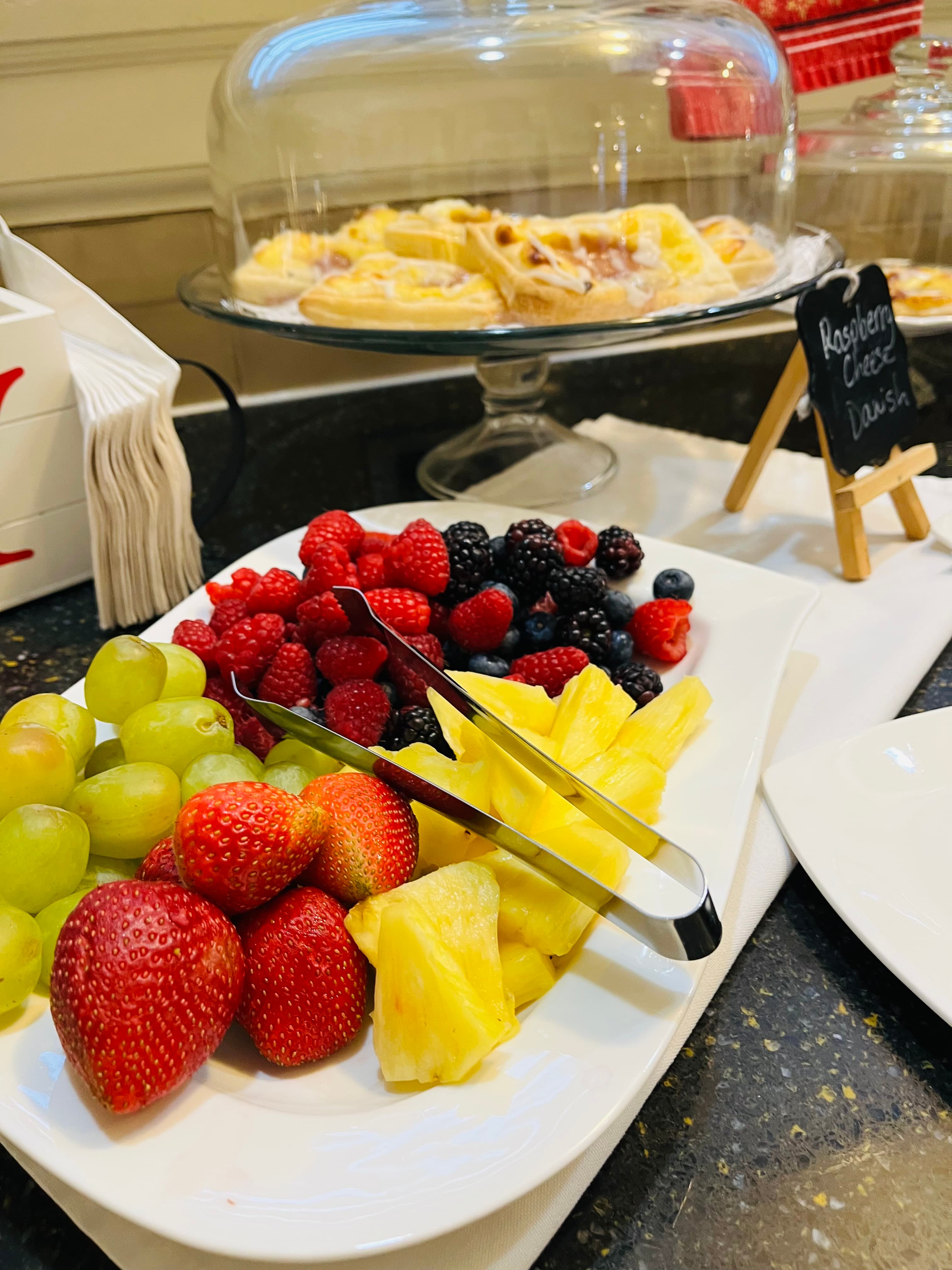 A platter of assorted fresh fruits, including grapes, strawberries, raspberries, blackberries, and pineapple.