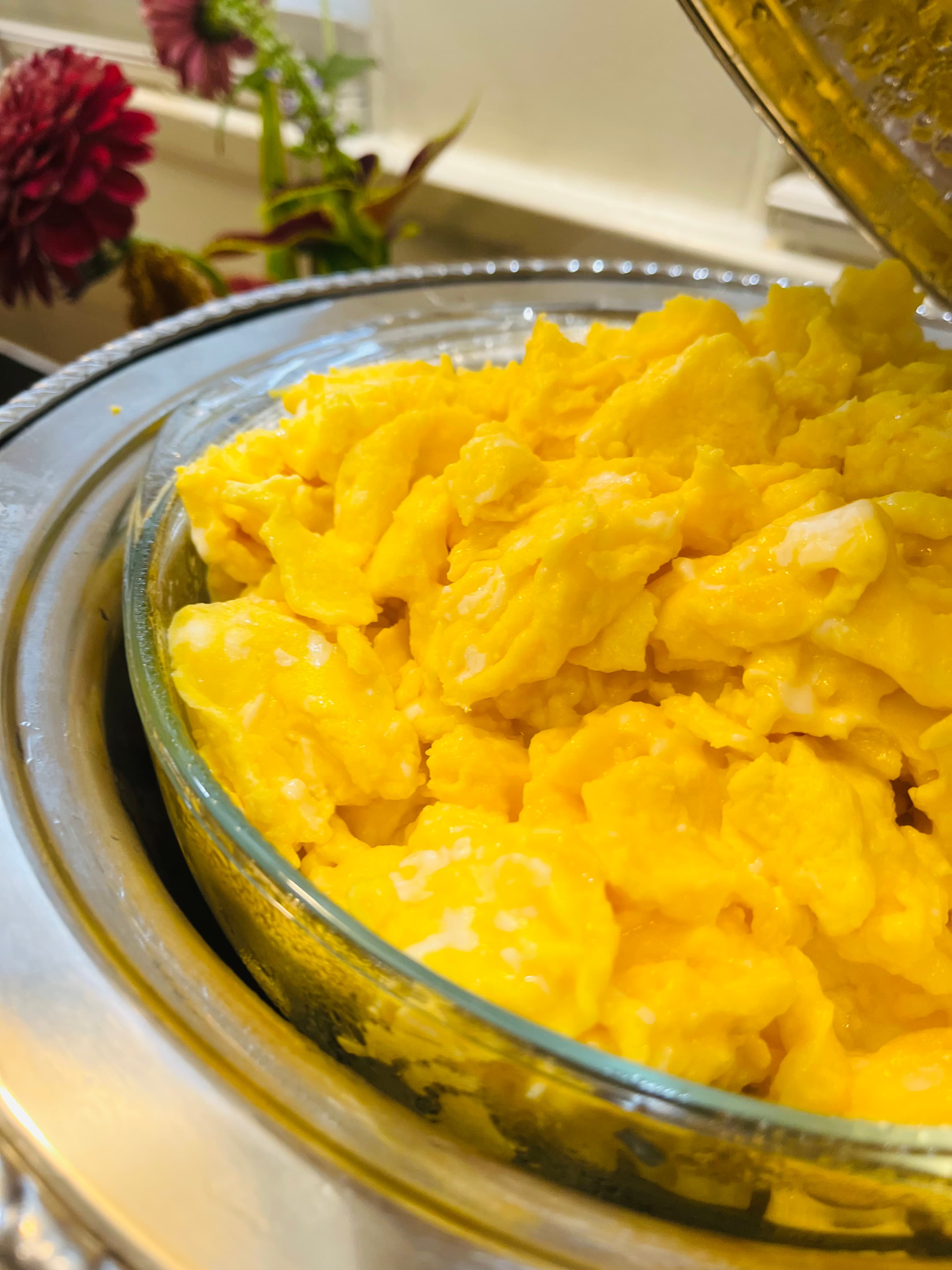 A close-up of fluffy scrambled eggs in a glass dish.