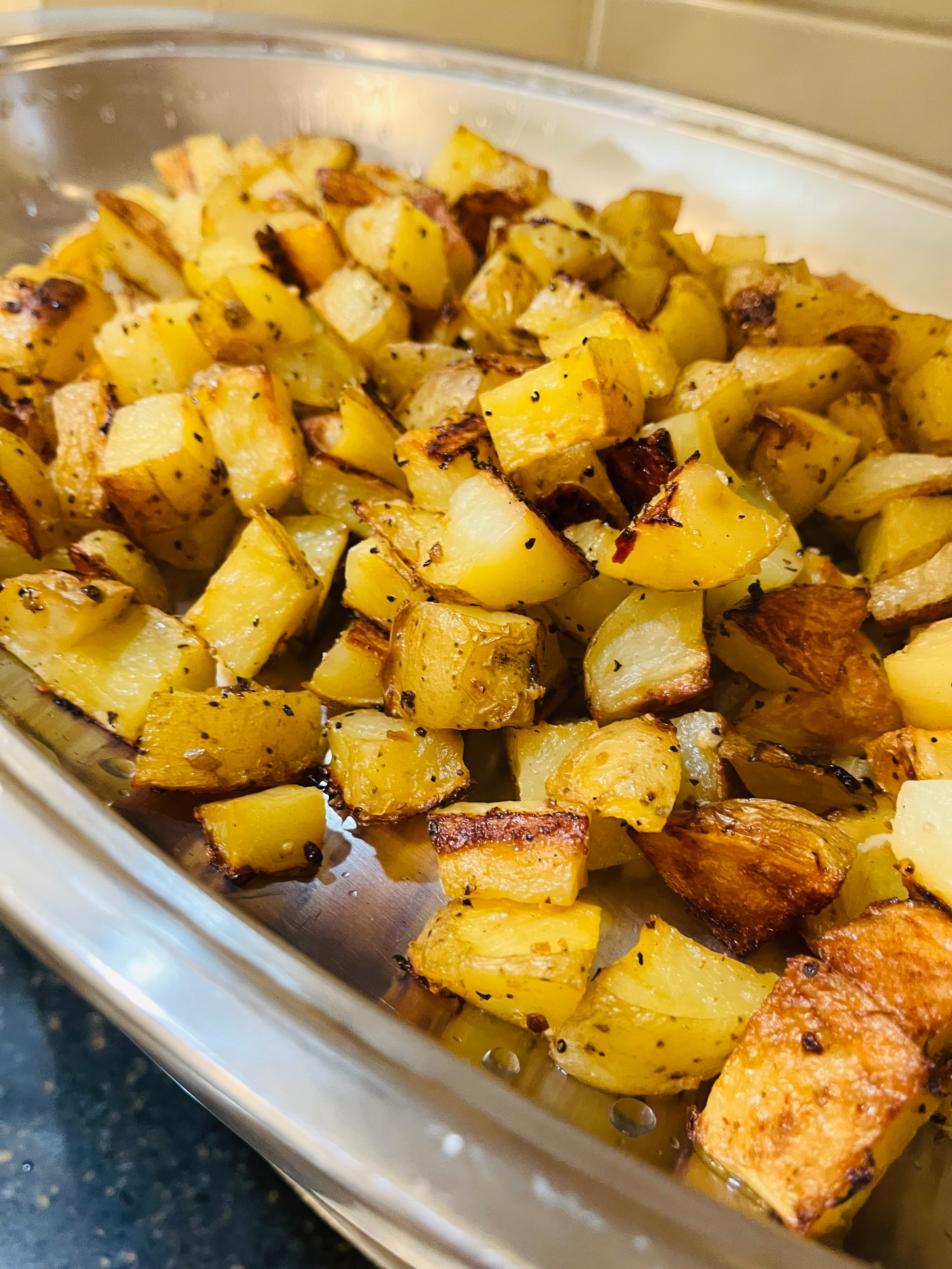 A dish of roasted, golden-brown diced potatoes seasoned with herbs.