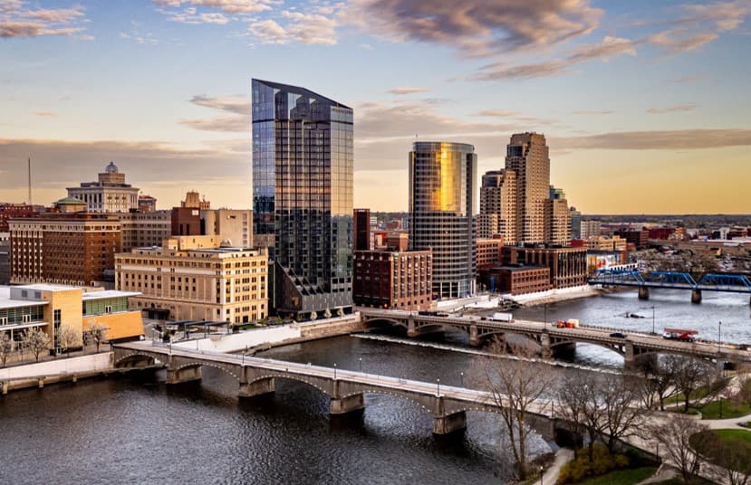 Aerial view of a city skyline at sunset with several high-rise buildings and a river.