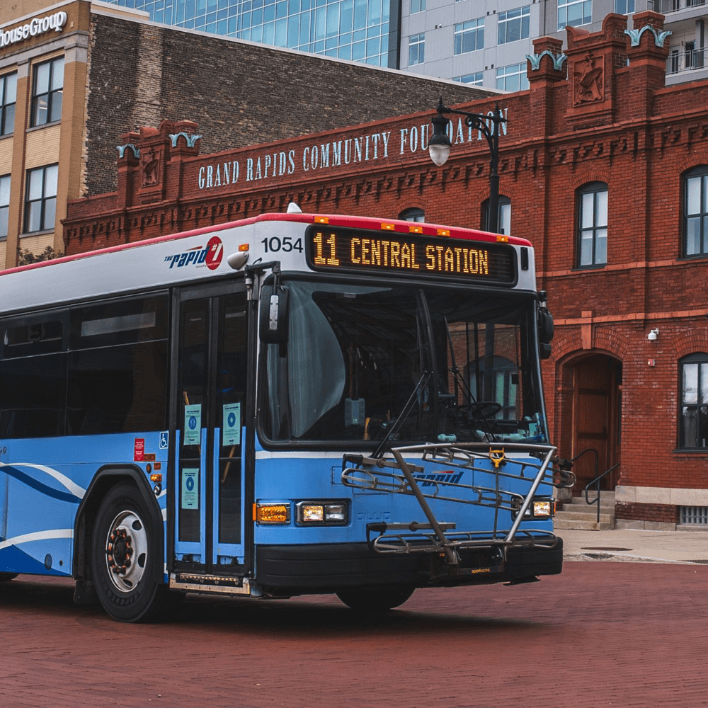 A blue public bus displaying the route number 11 to Central Station, in front of a brick building.