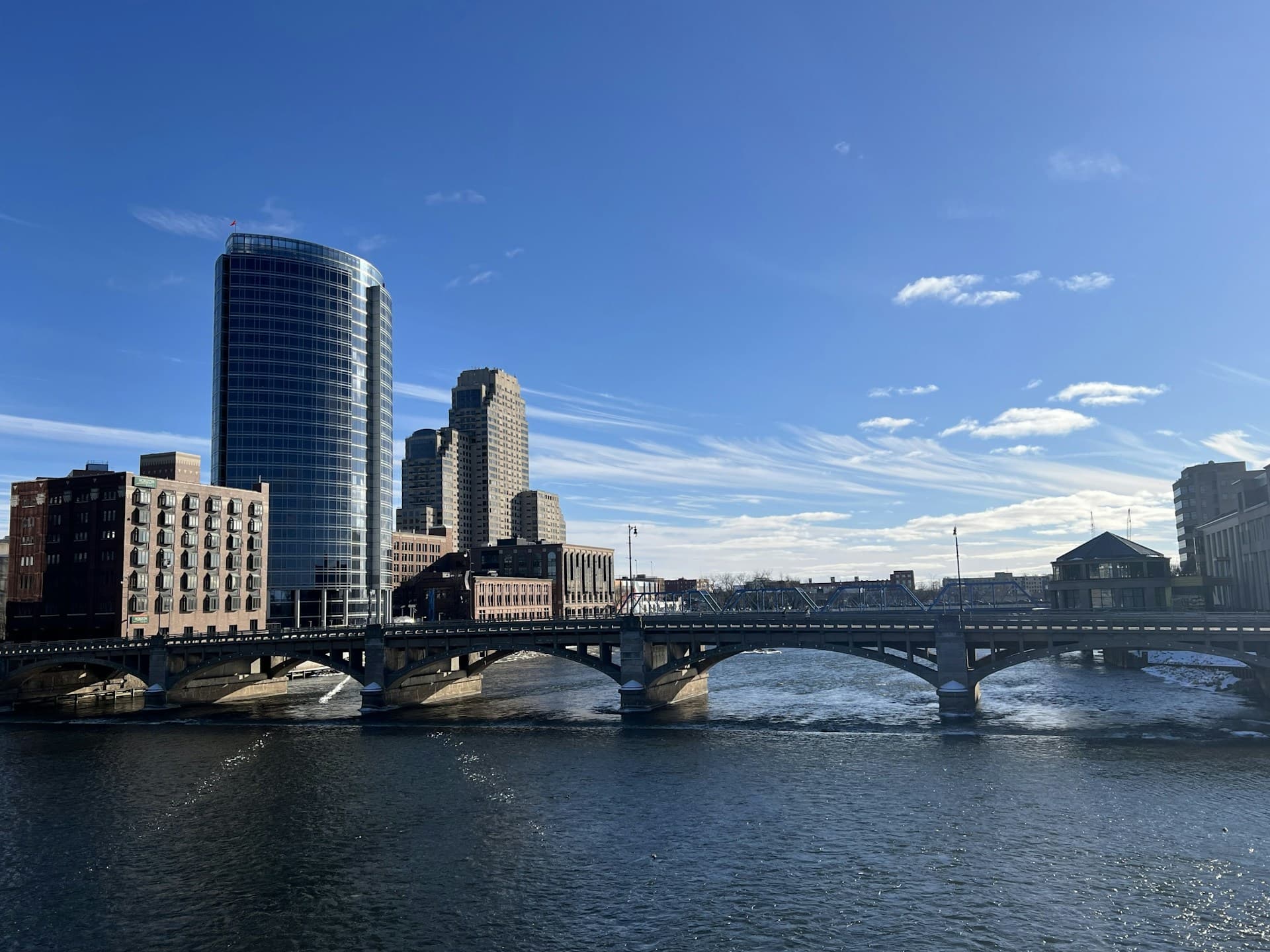 A skyline view featuring modern buildings alongside a river under a clear blue sky.