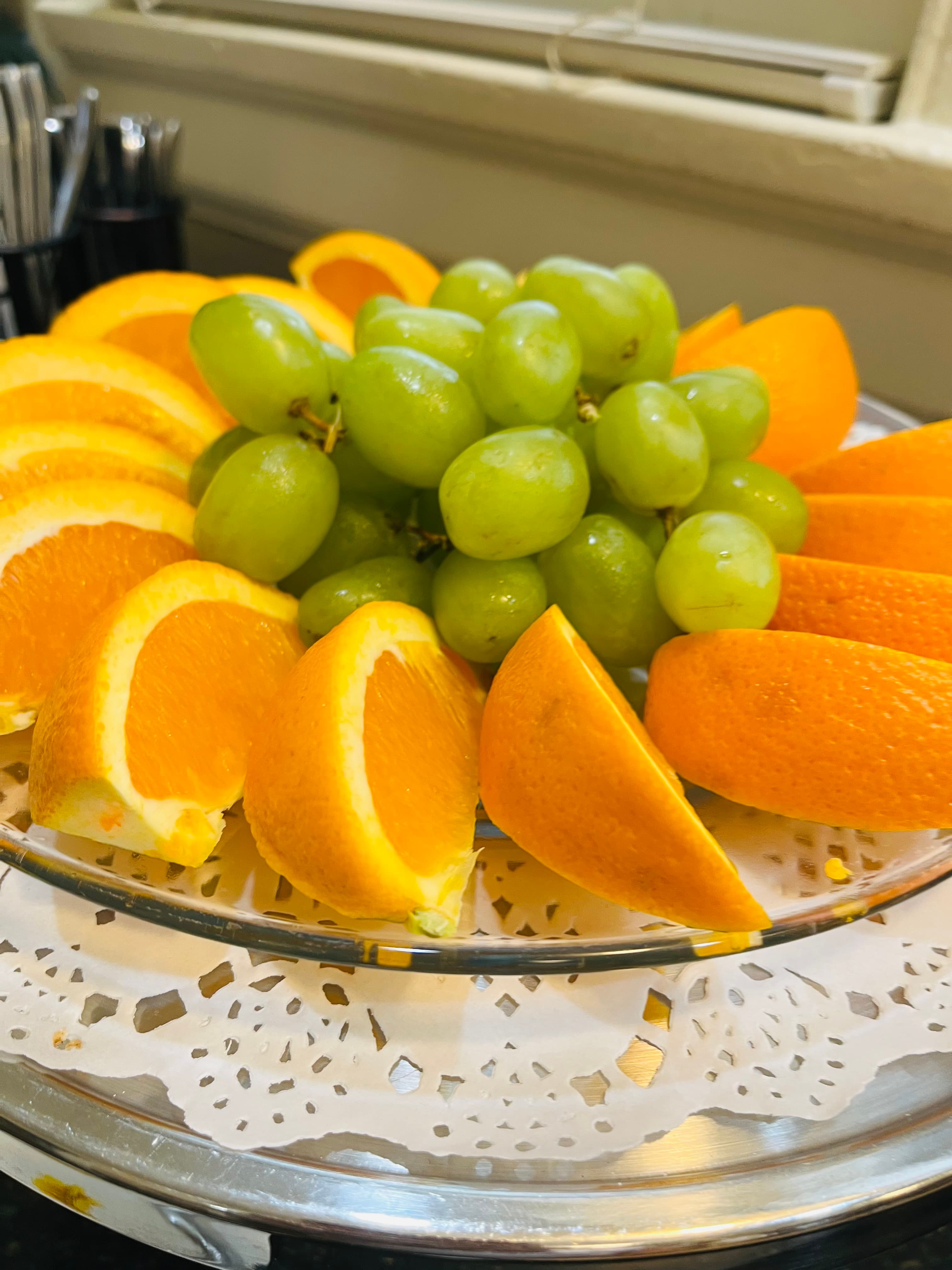 A decorative platter of orange slices and fresh green grapes.