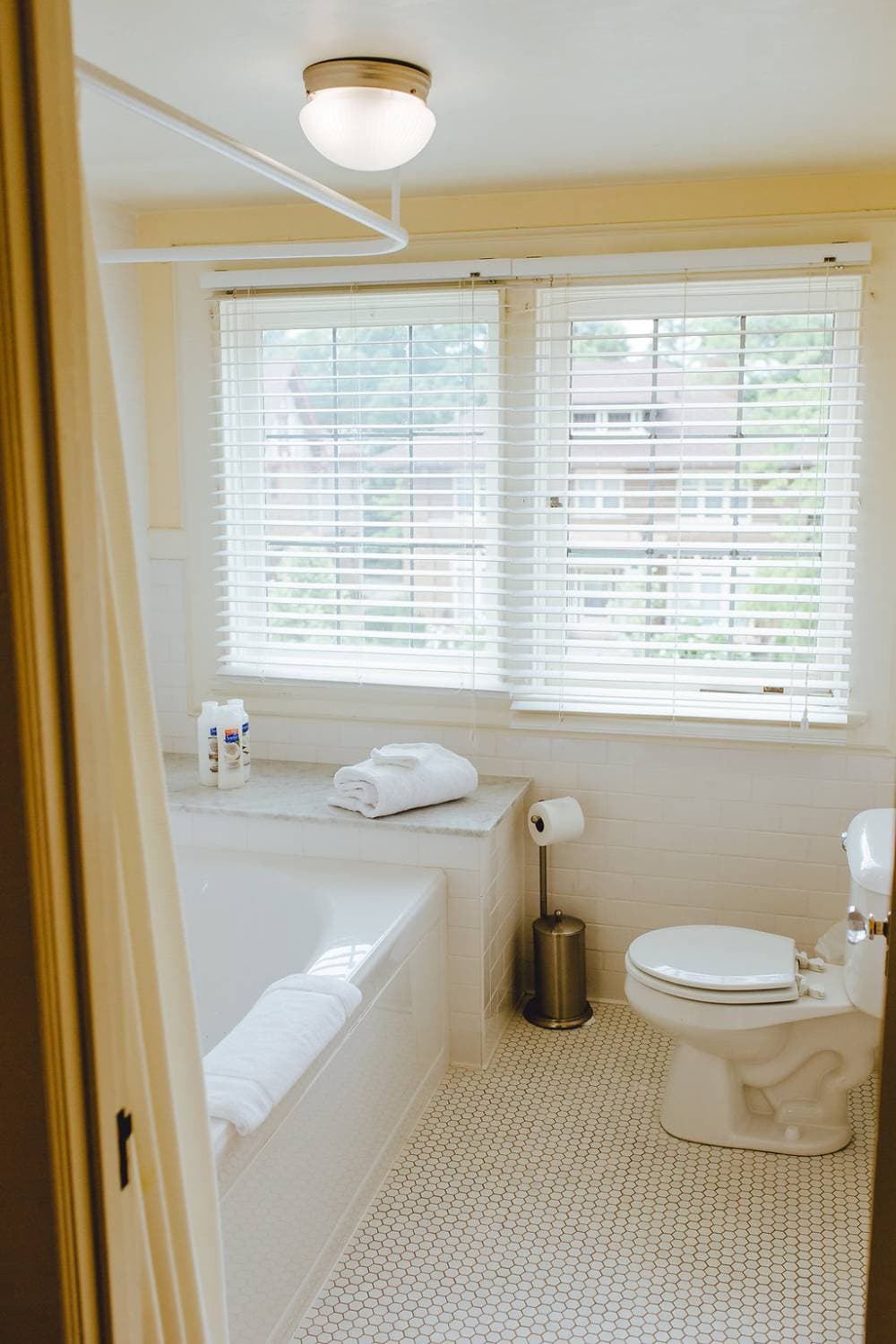 The ensuite bath with a jetted tub and heated floor between the in room sink and desk